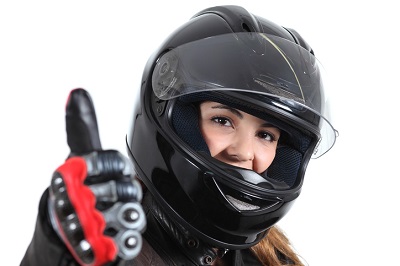 Woman wearing a black motorcycle helmet giving a thumbs up